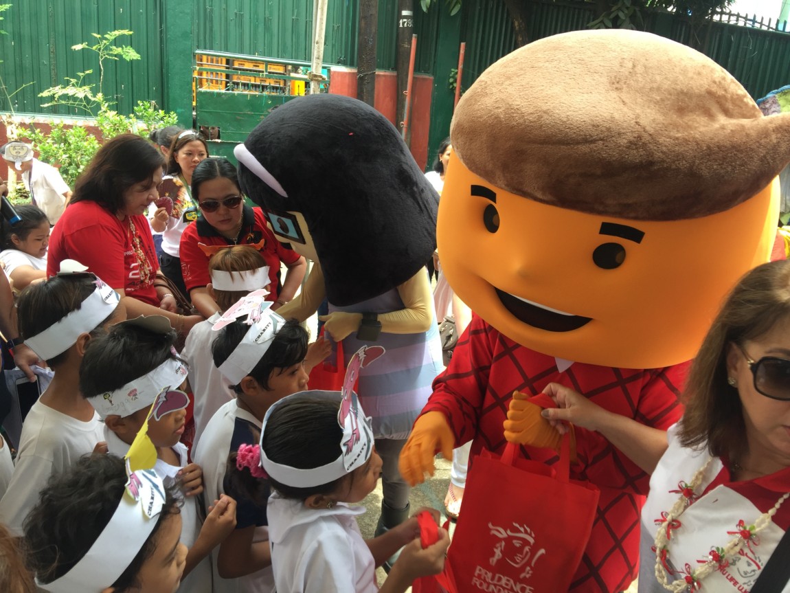 Cha Ching mascots giving goodie bags to students