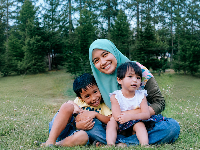 A mother smiling while holding her children