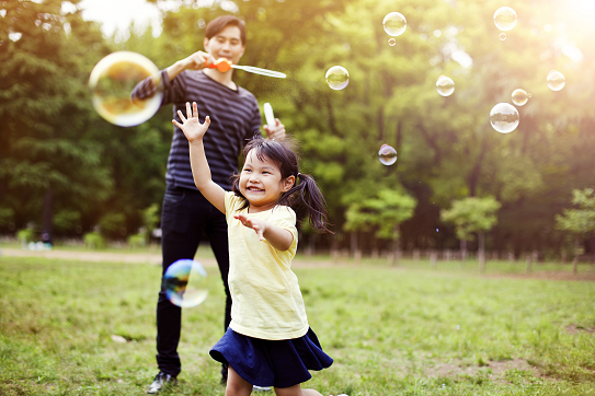 Father and daughter playing with bubbles.