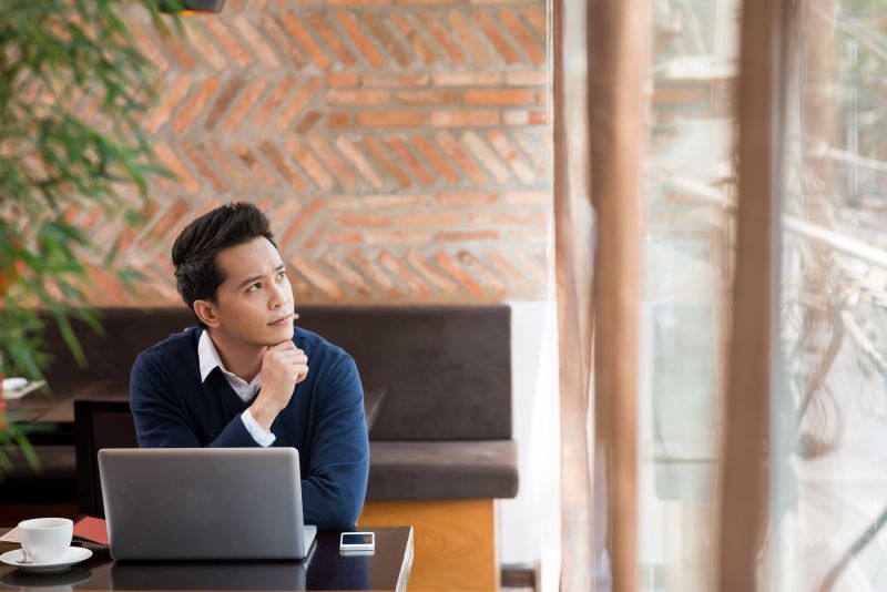 A man sitting on his desk in front of a laptop