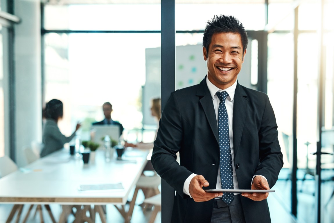 Asian man in office holding tablet